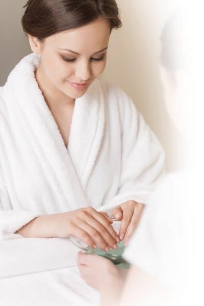 Woman Hands In Glass Bowl With Water On White Towel. Girl Holdin