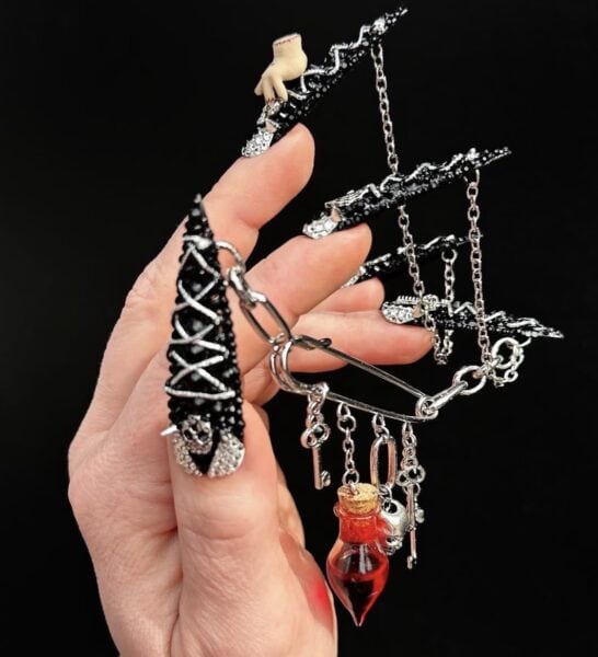 Hand with gothic black nails holding charm hair clip