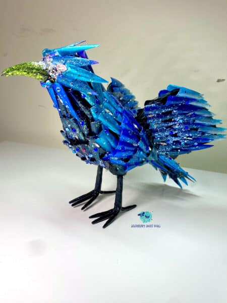 Blue glitter bird sculpture with bejewelled wings and green beak