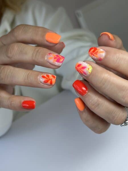 Hands displaying vivid orange and red floral nail art