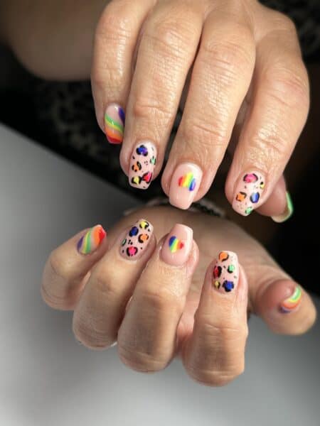 Hands displaying colourful rainbow and leopard print nail art