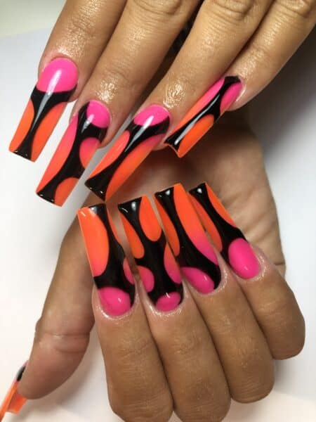 Hands with neon pink, orange and black acrylic nails