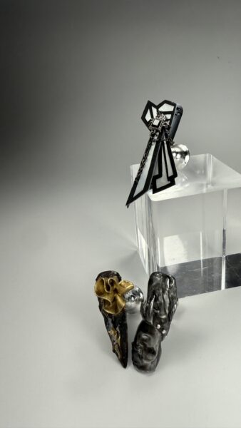 Black statement earrings displayed on clear acrylic stand