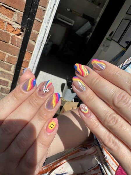 Hands displaying colourful rainbow and character nail art