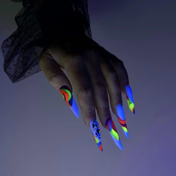 Hand displaying fluorescent multicoloured stiletto nails under UV light