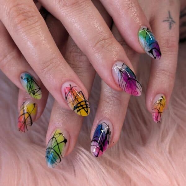 Hands displaying vibrant rainbow spiderweb nail art