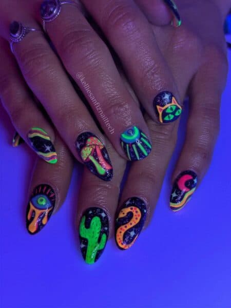 Hands with neon alien-themed nail art under ultraviolet light