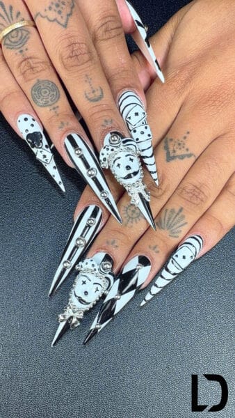 Tattooed hands displaying black and white stiletto nail art