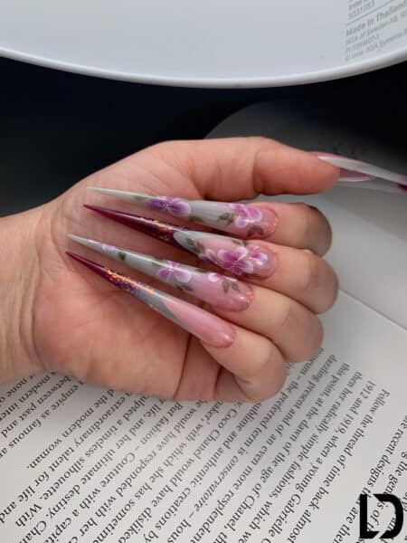 Hand displaying long floral pink and grey acrylic nails