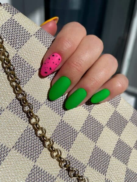 Neon green and pink acrylic nails holding patterned handbag