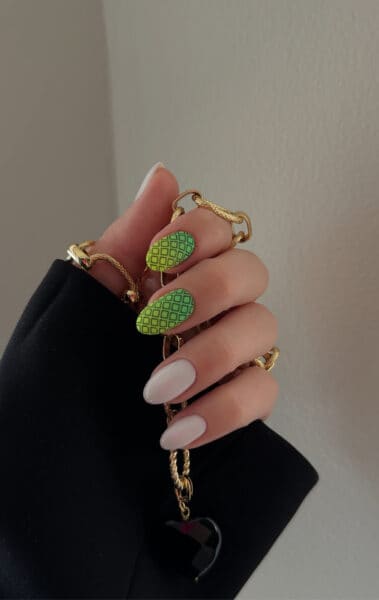 Hand holding gold chain with green patterned nail art