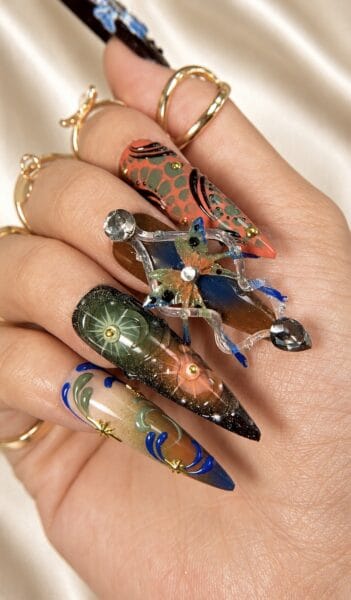 Hand displaying elaborate jeweled stiletto nail art