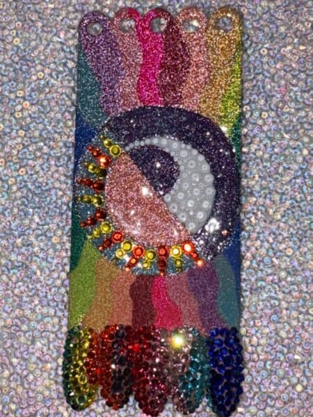 Glittery rainbow nail art with rhinestones and abstract design