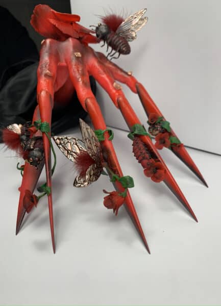 Red fairy figurine with metallic wings and poppies