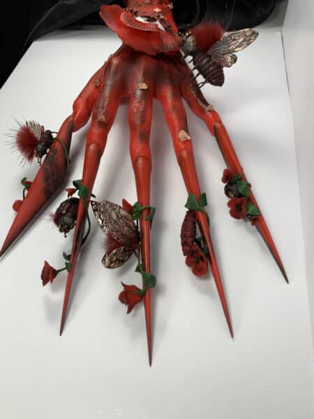 Red sculptural hands decorated with flowers and insects