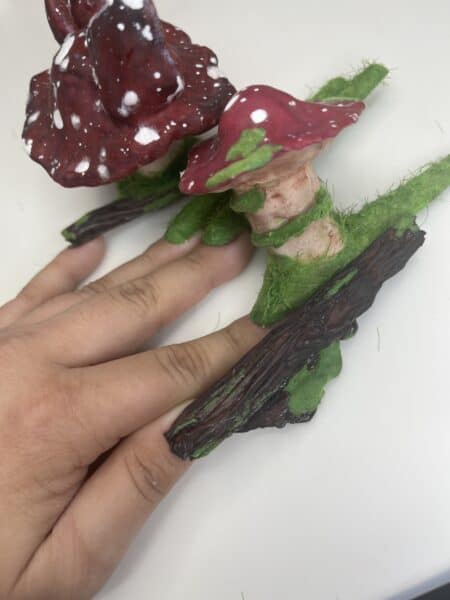 Hand holding red spotted mushroom house ornament