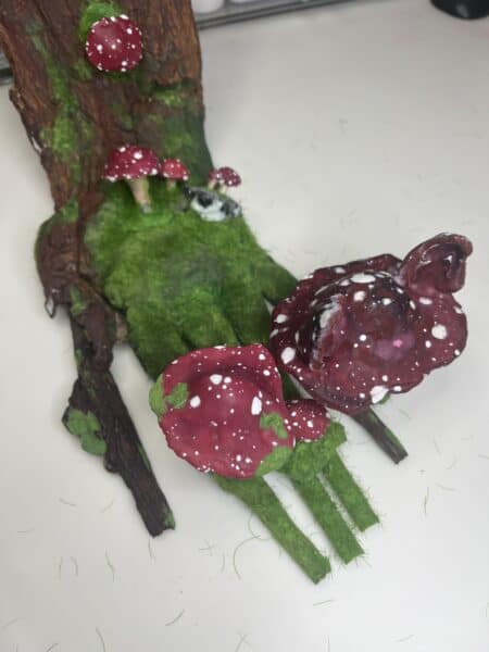 Handmade red spotted mushrooms on a mossy tree