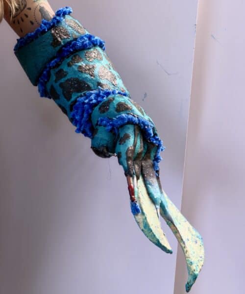 Turquoise and glitter body-painted performer in blue pom-pom costume