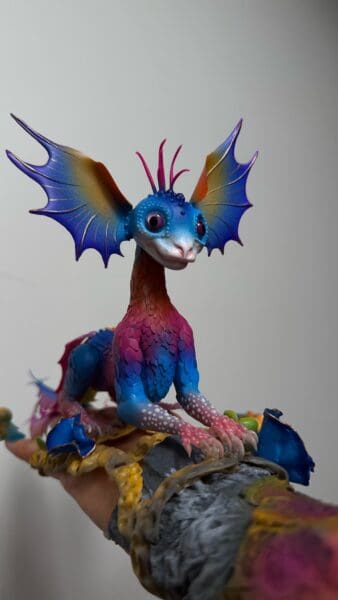 Colourful handmade dragon figurine with spread blue wings