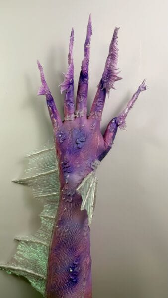 Purple fantasy hand with long sculpted claws and pearl decorations