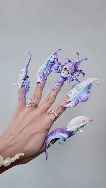 Hand with elaborate purple fantasy creature nail art