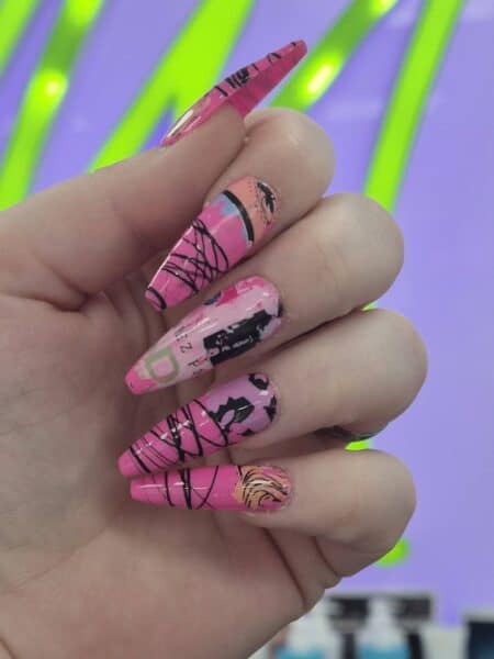 Hand displaying long pink graphic nail art