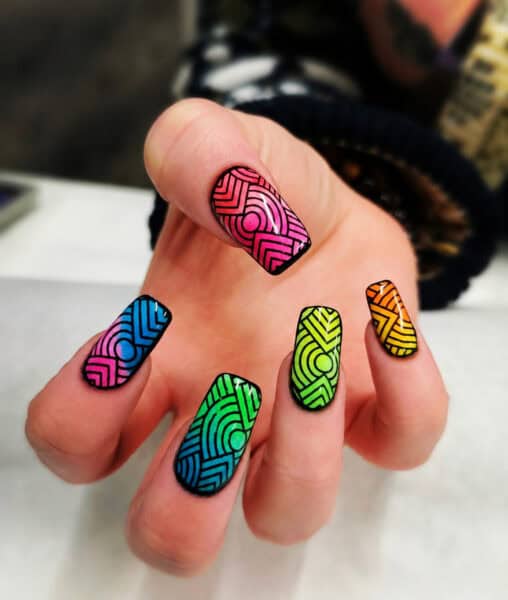 Hand displaying colourful geometric patterned nail art
