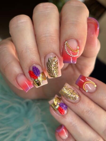 Colourful embellished nail art with feathers, rhinestones and gold leaves