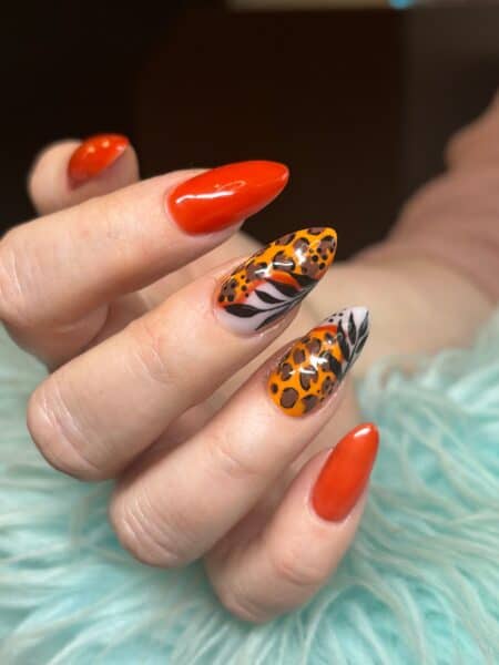 Hands displaying glossy orange, black and white nail art