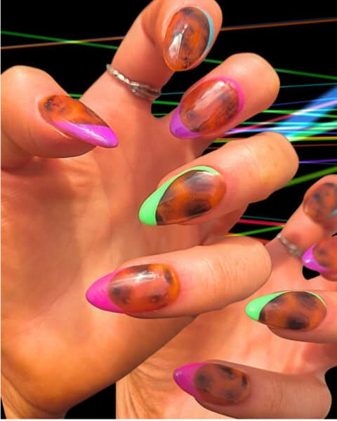 Hands with glossy tortoiseshell neon-tipped nails
