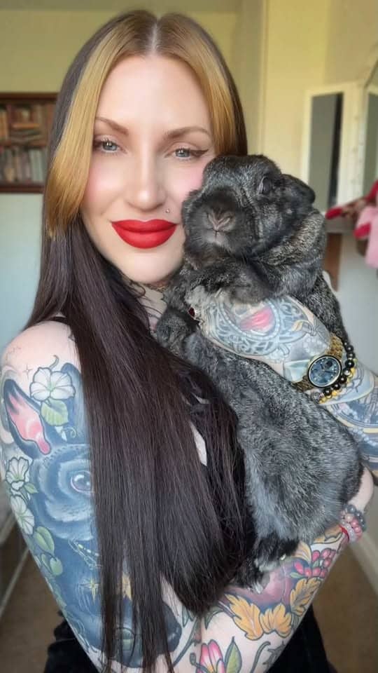 Tattooed woman holding a black lop-eared rabbit