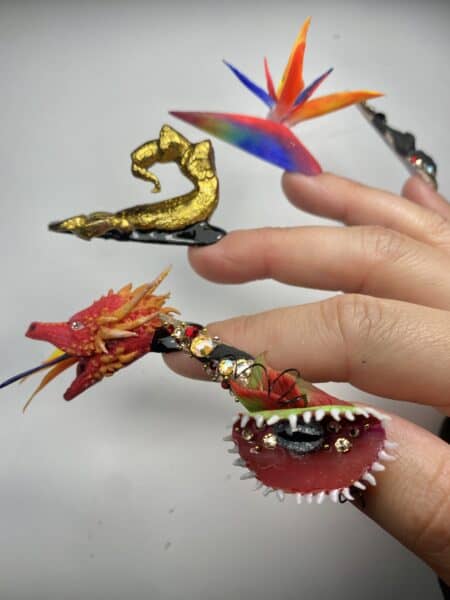 Dragon-themed 3D nail art with colourful feathers and rhinestones