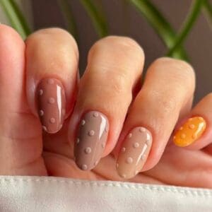 Close-up of polka-dot taupe and orange gel manicure