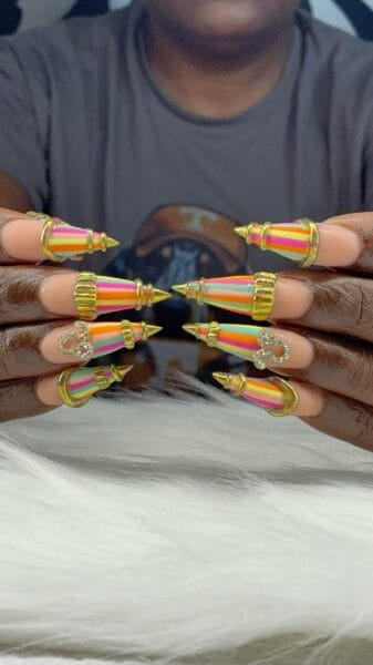 Neon striped stiletto nails with gold and rhinestone decorations