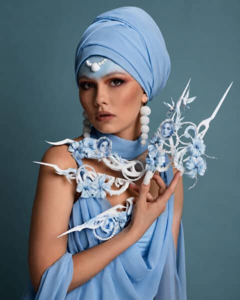 Woman in blue turban holding intricate floral sculpture