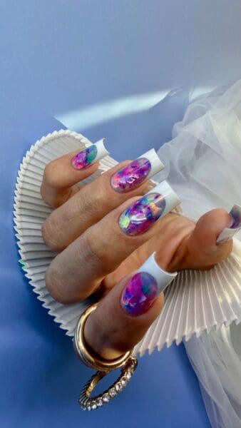 Hands with colourful abstract nail art and white French tips
