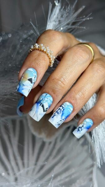 Hand with blue floral nails and gold pearl rings