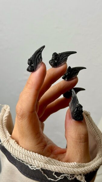 Hand with black gothic winged sculpted acrylic nails