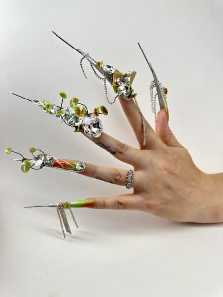 Hand displaying elaborate crystal and floral stiletto nail art