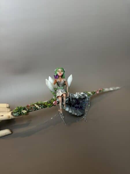 Handmade fairy figurine sitting on a flower-covered branch