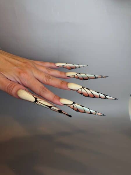 Hands displaying long ivory, black and gold patterned nails