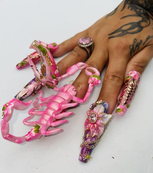 Hand with extravagant pink floral acrylic nail extensions
