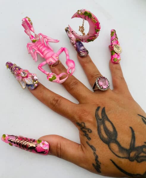 Hand with elaborate pink scorpion and floral nail art