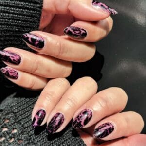 Hands with pink and black crackle-pattern manicure