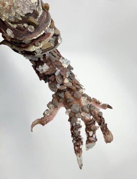 Crystal and pebble-encrusted sculptural hand against white background