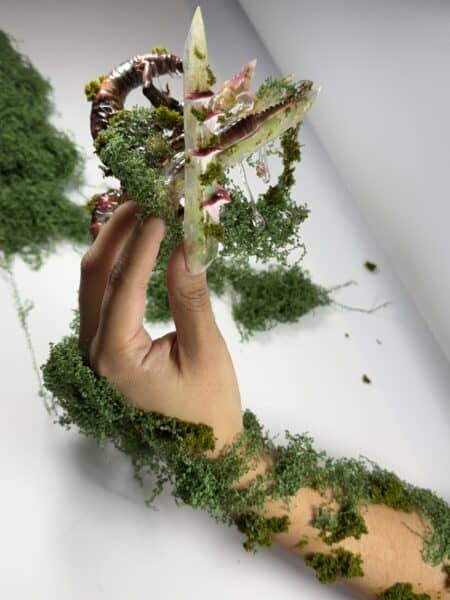 Hand holding moss-covered fairy house with pink mushrooms