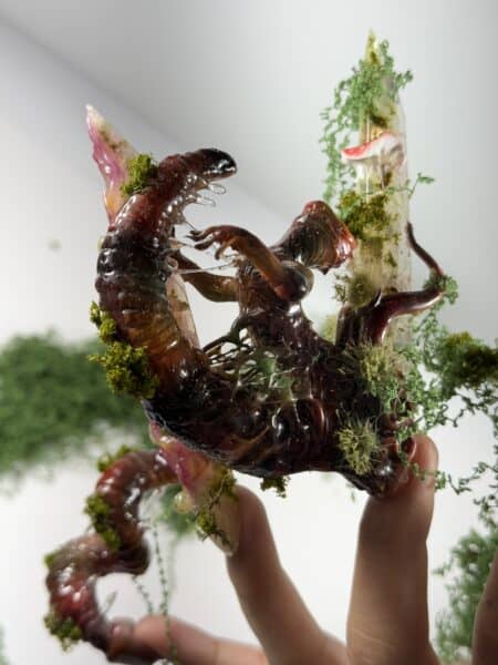 Hands holding moss-covered translucent organic sculpture