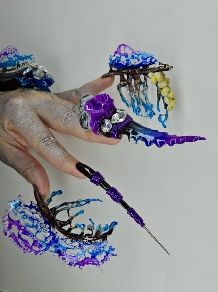 Hand displaying elaborate blue and purple sculpted nail art