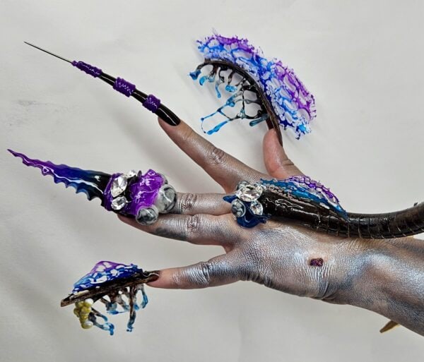 Hand displaying elaborate purple and blue sculpted nail art