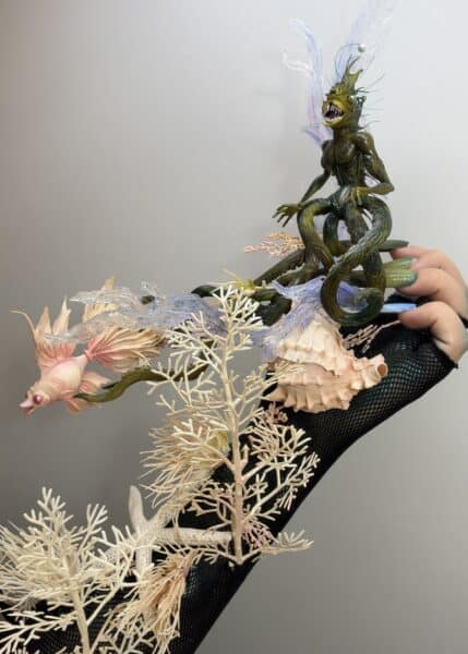 Handheld aquatic monster figurine surrounded by coral and translucent waves